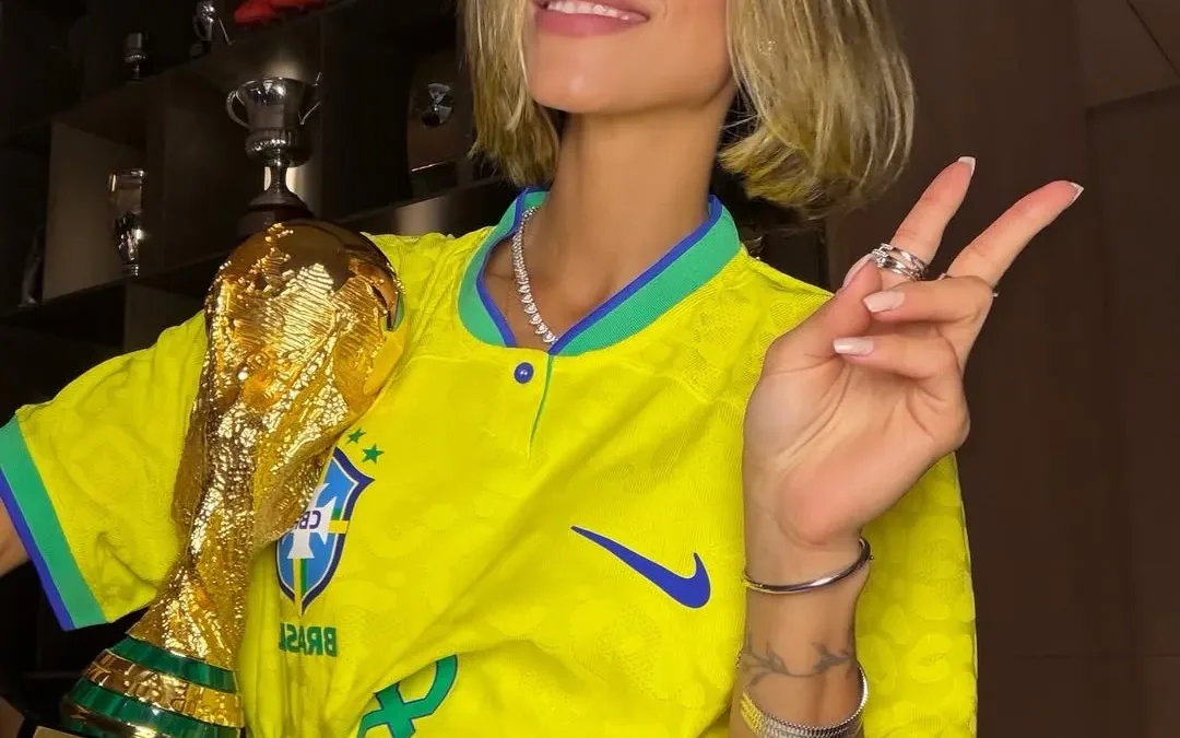 Carol Leite exibe estilo com camisa de Kaká e réplica da taça da Copa do Mundo