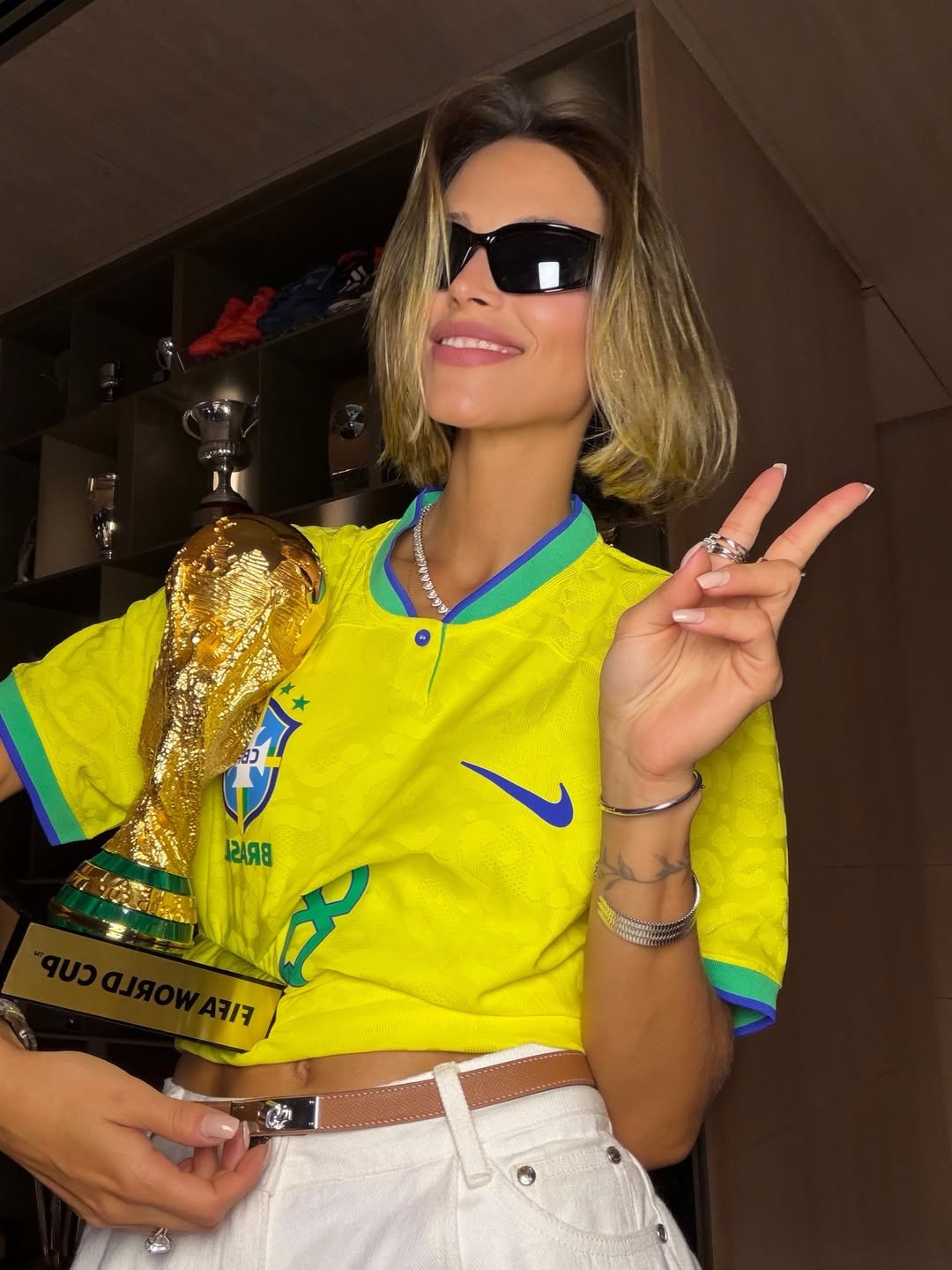 Carol Leite exibe estilo com camisa de Kaká e réplica da taça da Copa do Mundo